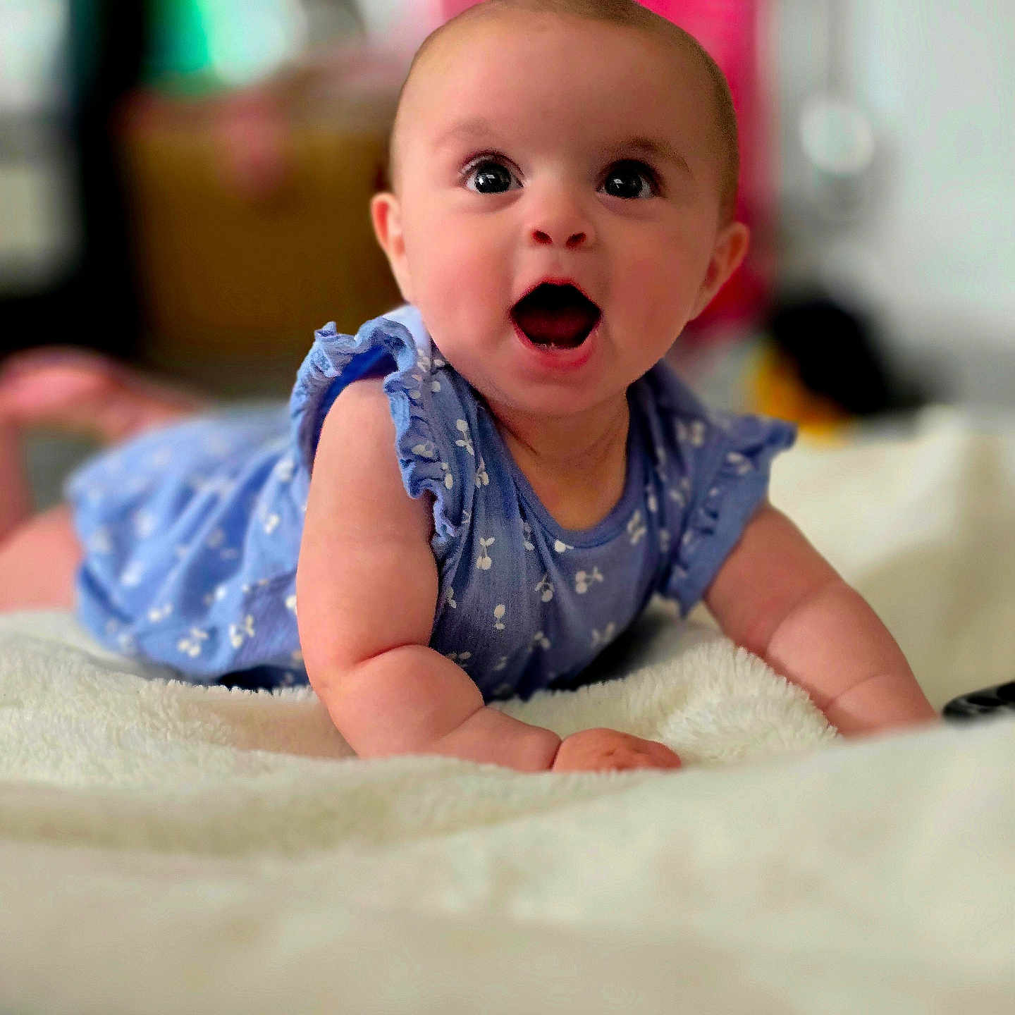 Lexi-Mae is registered to the contest to win money with this photo: baby, blanket, blue_dress, child, closeup, clothing, cute, expression, face, happy, indoors, infant, lying_down, person, portrait, skin, smiling, soft_texture, toddler, wide_eyes
