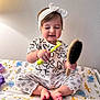 Allison is registered to the contest to win money with this photo: toddler, child, baby, toothbrush, hairbrush, headband, bow, floral_clothing, sitting, blanket, animal_pattern, feet, indoor, wall, playful, cute, person, smile, portrait, young_child