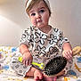toddler, child, baby, headband, bow, toothbrush, hairbrush, blanket, animal_print, sitting, indoors, cute, expression, clothing, patterned_pants, patterned_shirt, barefoot, face, person, playful