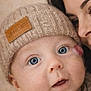 baby, infant, adult, blue_eyes, beanie, knit_hat, hand, sweater, cozy, close_up, portrait, cheek_mark, parent, cuddling, indoor, beige_background, eyelashes, gaze, mouth_open, skin