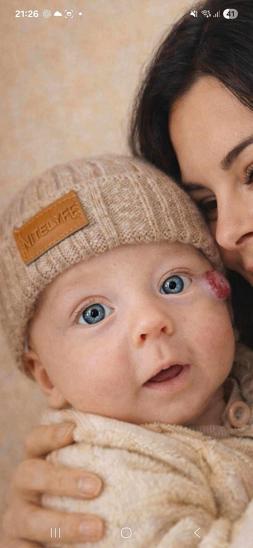 Aymen a rejoint le concours — aidez-le/la à gagner de superbes lots ! baby, infant, adult, blue_eyes, beanie, knit_hat, hand, sweater, cozy, close_up, portrait, cheek_mark, parent, cuddling, indoor, beige_background, eyelashes, gaze, mouth_open, skin