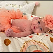 Rheane participe au concours pour gagner de l'argent avec cette photo : baby, infant, tutu, headband, flower, smile, blanket, pattern, cute, lying_down, soft, adorable, child, young, skin, happy, indoors, cozy, fashion, accessory