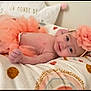 baby, infant, tutu, headband, flower, smile, blanket, pattern, cute, lying_down, soft, adorable, child, young, skin, happy, indoors, cozy, fashion, accessory