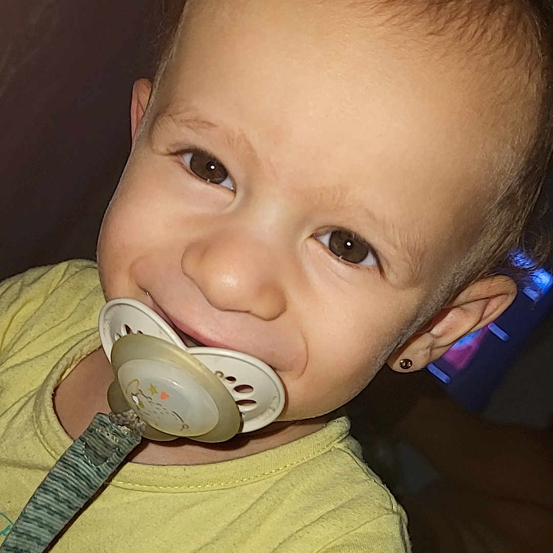 Maylan participe au concours pour gagner de l'argent avec cette photo : baby, child, closeup, cute, earring, expression, eyes, face, happy, head, indoor, mouth, pacifier, person, portrait, skin, smile, toddler, yellow_shirt, young_child