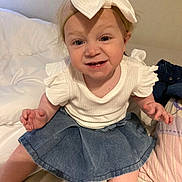 Adèle participe au concours pour gagner de l'argent avec cette photo : toddler, child, baby, headband, bow, denim_skirt, white_shirt, bed, pillow, blanket, smiling, funny_face, indoor, person, cute, sitting, clothing, skin, hair, happy