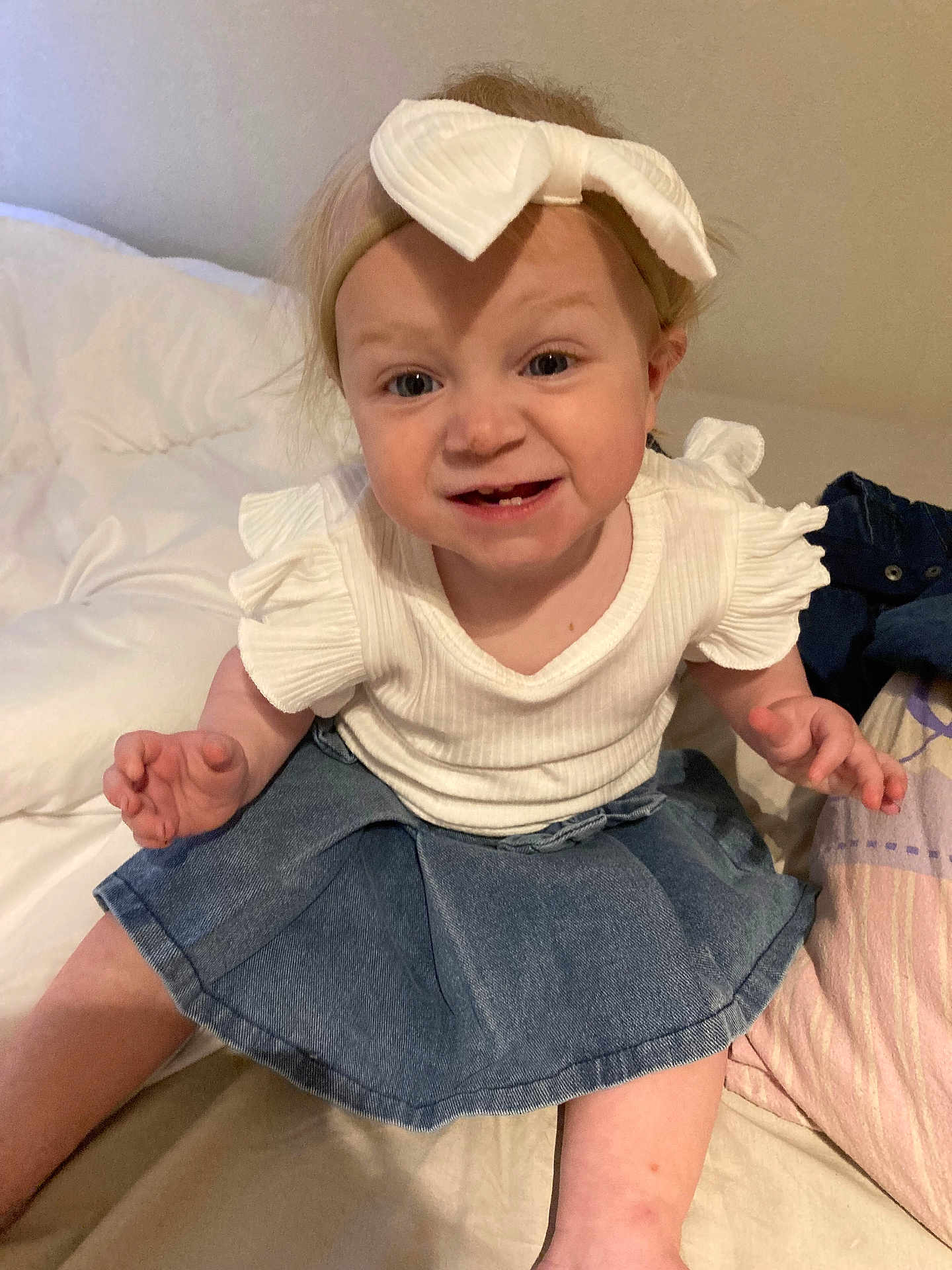 Adèle participe au concours pour gagner de l'argent avec cette photo : toddler, child, baby, headband, bow, denim_skirt, white_shirt, bed, pillow, blanket, smiling, funny_face, indoor, person, cute, sitting, clothing, skin, hair, happy