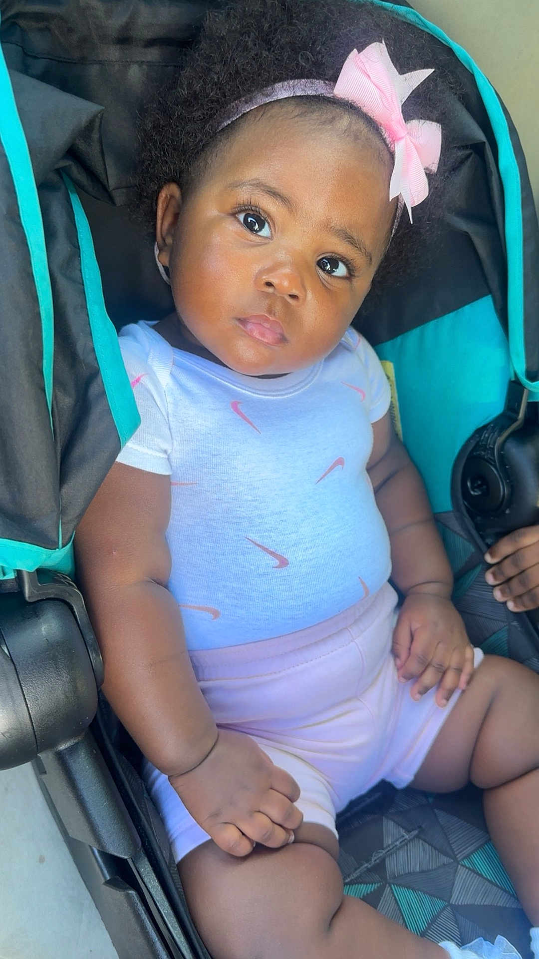 Jalani joined the competition — help win amazing prizes! baby, child, stroller, pink_bow, headband, white_shirt, shorts, curly_hair, sitting, cute, portrait, infant, hand, legs, black_skin, outdoor, sunlight, expression, clothing, baby_clothes