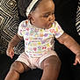 Jalani joined the competition — help win amazing prizes! baby, child, infant, girl, headband, bow, curly_hair, sitting, couch, clothing, shorts, patterned_shirt, cute, indoors, sock, white_sock, black_background, curious, portrait, person