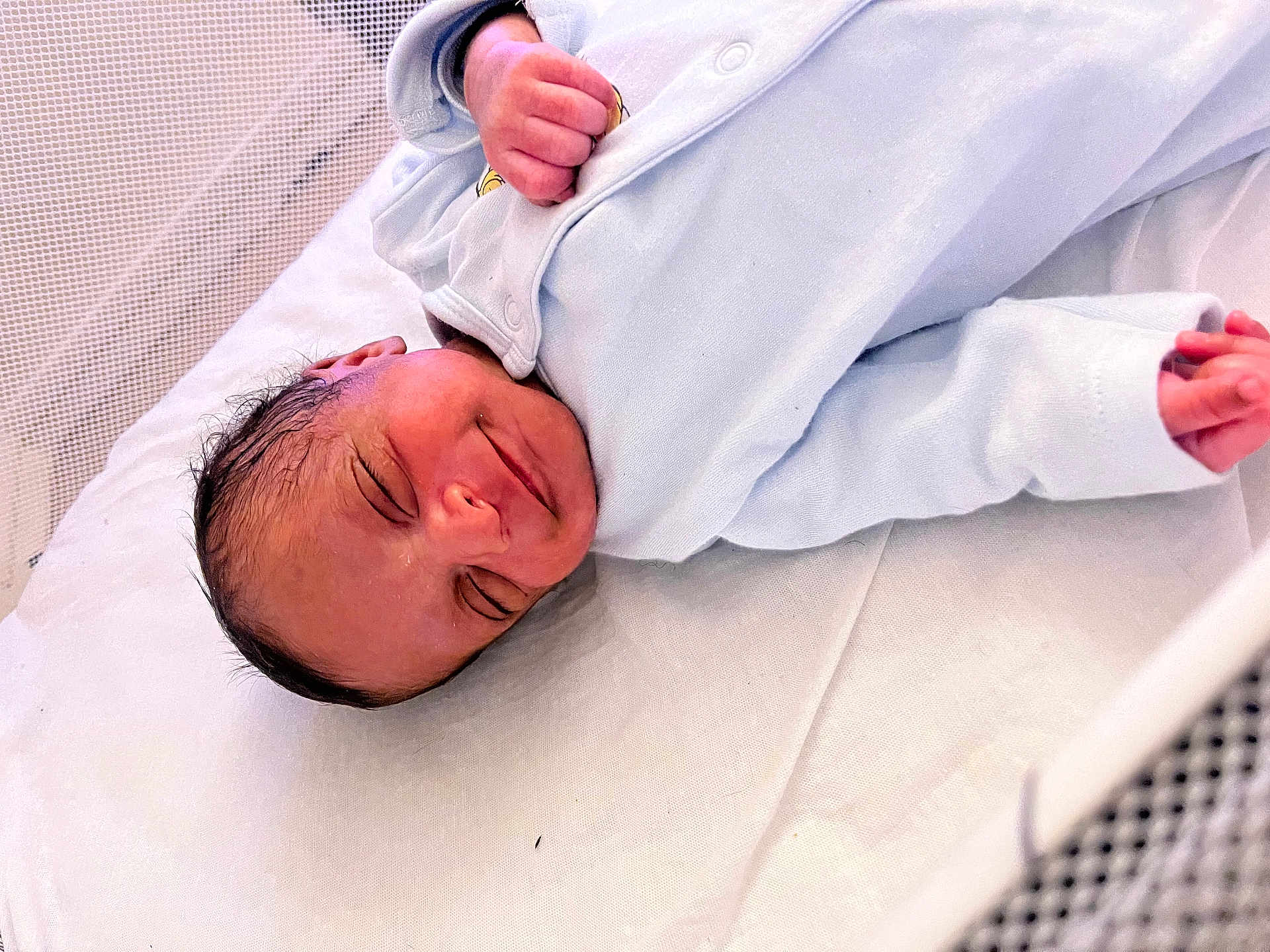 Kelysha participe au concours pour gagner de l'argent avec cette photo : newborn, baby, infant, sleeping, smiling, wrapped, blanket, blue_clothing, crib, mesh, bed, soft, peaceful, face, head, hand, skin, resting, indoors, cute