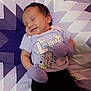 baby, infant, sleeping, smile, mittens, purple, shirt, pattern, quilt, geometric_pattern, bed, child, cute, happy, relaxing, portrait, small_person, soft_lighting, indoor, resting
