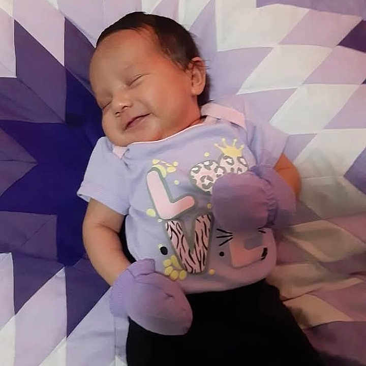 Kailecelove is registered to the contest to win money with this photo: baby, bed, child, cute, geometric_pattern, happy, indoor, infant, mittens, pattern, portrait, purple, quilt, relaxing, resting, shirt, sleeping, small_person, smile, soft_lighting