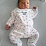 Nino participe au concours pour gagner de l'argent avec cette photo : baby, infant, onesie, white_clothing, red_hearts, lying_down, soft_surface, face, cute, child, newborn, person, sleepwear, bed, expression, calm, small_hands, footed_pajamas, indoors, portrait