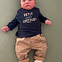 baby, infant, child, clothing, shirt, pants, shoes, sneakers, lying_down, green_background, face, hands, feet, casual_wear, expressionless, indoor, portrait, young_child, cute, small