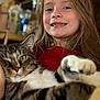 Boots joined the competition — help win amazing prizes! child, girl, cat, tabby_cat, pet, portrait, close_up, smile, long_hair, indoor, cuddling, paw, fur, whiskers, eyes, red_shirt, home, happy, person, animal_face