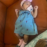 Legacy joined the competition — help win amazing prizes! baby, infant, pacifier, headband, flower, dress, blue_dress, pink_socks, couch, orange_couch, hand, skin, patterned_cushion, lying_down, indoors, cute, small, newborn, child, cozy