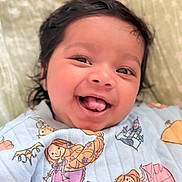 Isha is registered to the contest to win money with this photo: baby, infant, smiling, tongue_out, onesie, princess, illustration, hair, face, cheerful, cute, child, happy, lying_down, blanket, fabric, pattern, portrait, indoors, closeup