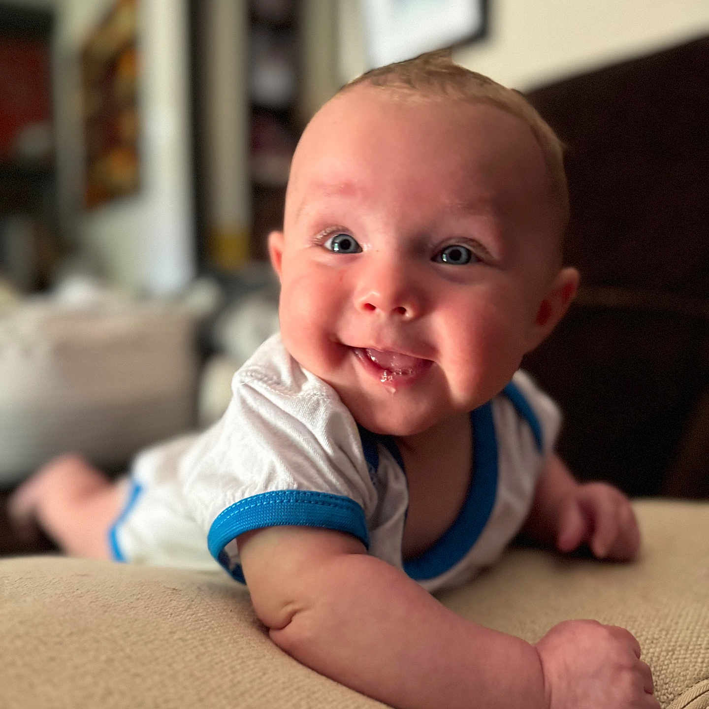 Elijah joined the competition — help win amazing prizes! arm, baby, blue_trim, child, couch, cute, drool, face, furniture, happy, indoor, infant, living_room, person, portrait, skin, smiling, toddler, white_clothing, young