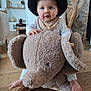 Lilio participe au concours pour gagner de l'argent avec cette photo : baby, child, hat, blue_eyes, bib, rocking_toy, elephant_toy, plush_toy, wooden_floor, indoor, furniture, living_room, decor, footwear, cute, smiling, seated, person, playtime, cozy