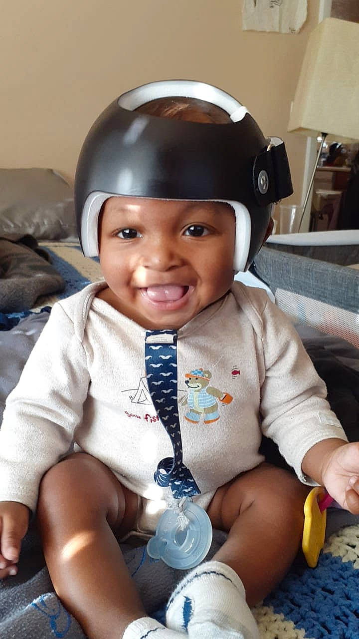 Dakari is registered to the contest to win money with this photo: arm, baby, baby_toddler_clothing, cheek, child, comfort, eye, fun, gesture, happy, headwear, helmet, joy, mouth, person, personal_protective_equipment, skin, sleeve, smile, sports_gear