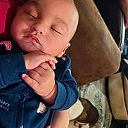 Rj is registered to the contest to win money with this photo: newborn, baby, sleeping, infant, portrait, face, hands, blue_clothing, onesie, car, cuddling, peaceful, indoors, dog, pet, close_up, family, soft_lighting, resting, cute
