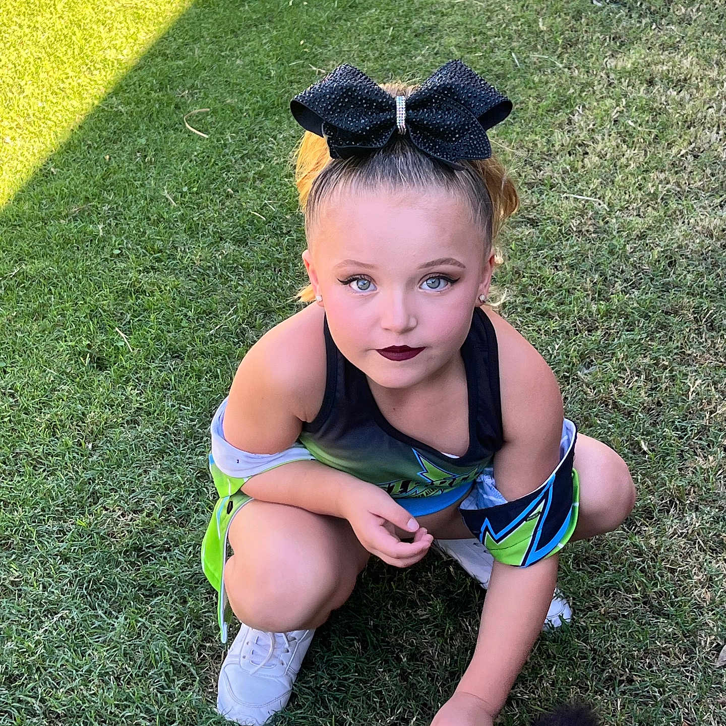 Abriella is registered to the contest to win money with this photo: animal_tail, black_bow, blue_eyes, casual, child, cute, fashion, girl, grass, greenery, makeup, outdoor, pet, playful, portrait, sporty_outfit, squatting, sunlight, white_sneakers, young