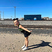 Abriella joined the competition — help win amazing prizes! child, girl, outdoor, sporty, cheerleader, shadow, gravel, train_tracks, blue_sky, sunny, playful, smiling, white_shoes, black_skirt, hair_bow, daylight, posing, young, fun, casual