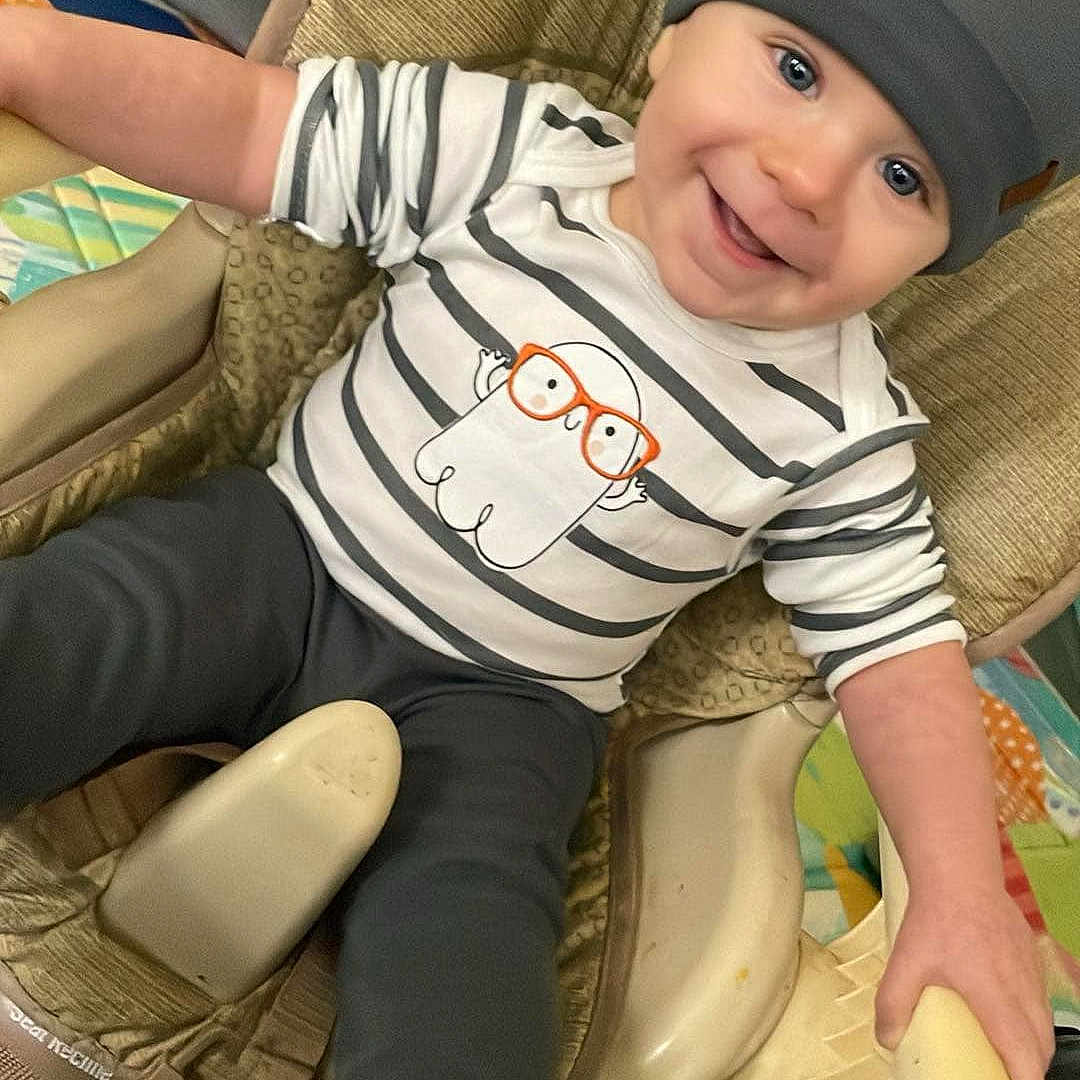Shiloh is registered to the contest to win money with this photo: baby, cap, chair, clothing, couch, cushion, face, furniture, happy, hat, head, homedecor, hosiery, pants, person, photography, portrait, sitting, sock, t_shirt