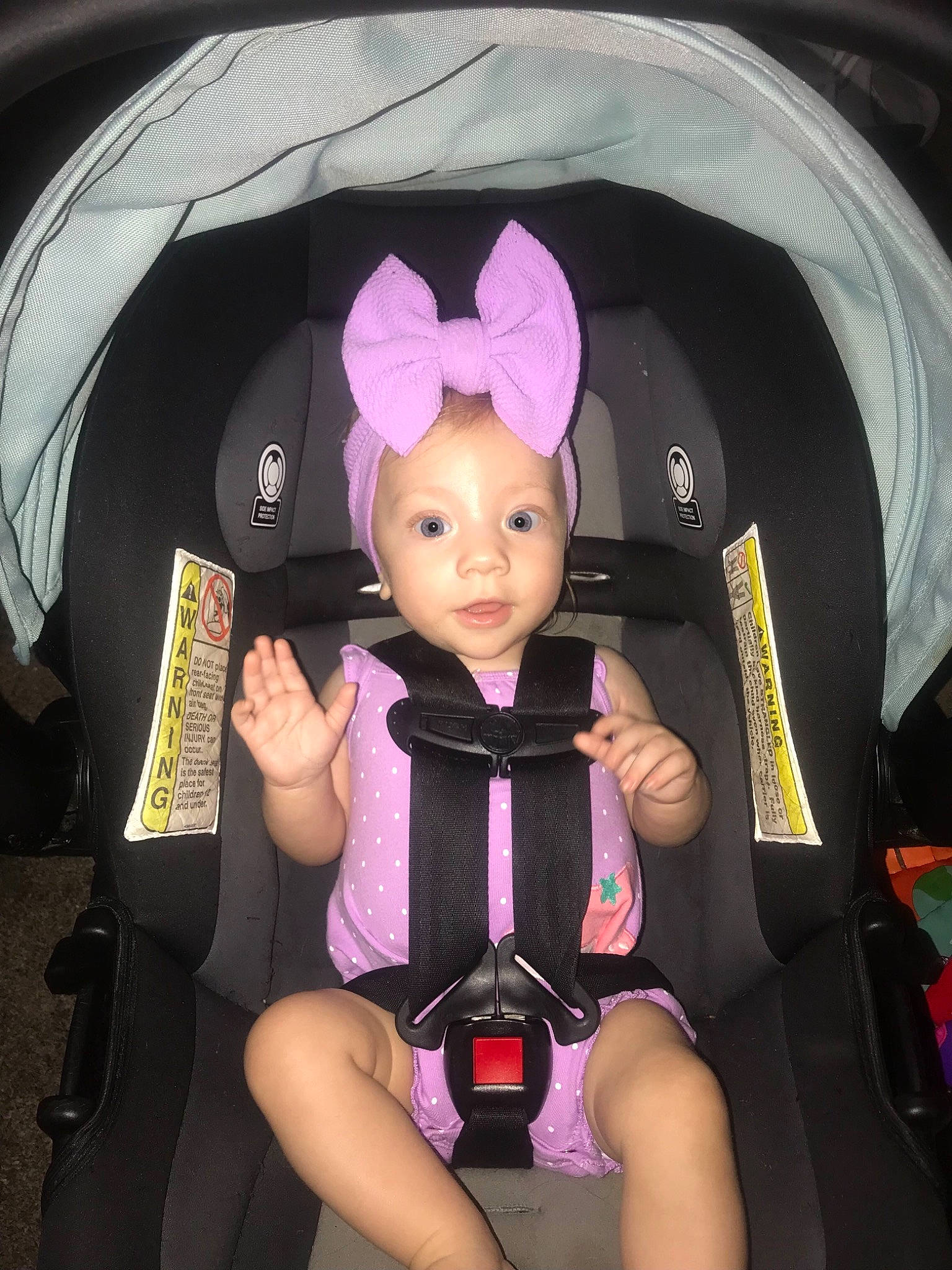 Macie is registered to the contest to win money with this photo: auto_part, baby_products, baby_toddler_clothing, black_hair, car_seat, chair, child, doll, fashion_accessory, fun, headwear, lap, magenta, person, pink, product, purple, sitting, thigh, thumb
