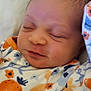 Nova is registered to the contest to win money with this photo: baby, sleeping, infant, onesie, clothing, patterned_clothing, fruit_pattern, orange, blue, white_blanket, soft_texture, closeup, resting, peaceful, newborn, child, face, head, skin, person