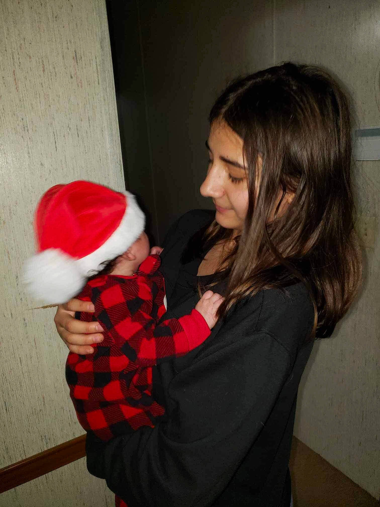 Elliana joined the competition — help win amazing prizes! arm, cap, carmine, child, christmas, christmas_eve, event, fun, fur, gesture, happy, holiday, layered_hair, pattern, person, plaid, santa_claus, sitting, smile, tartan