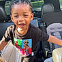 child, smiling, car_interior, seat, child_seat, braided_hair, tshirt, black_pants, sunlight, happy, person, indoor, vehicle, seatbelt, seat_cushion, portrait, young, casual_clothing, fun, daylight