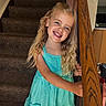 child, girl, smiling, blonde_hair, curly_hair, dress, blue_dress, stairs, carpet, wooden_railing, indoor, home, railing, person, happy, portrait, standing, young, cute, smile