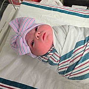 Selina is registered to the contest to win money with this photo: newborn, baby, swaddled, hat, bow, striped_blanket, hospital, bassinet, medical_equipment, infant, cute, sleeping, person, face, bed, blanket, indoors, headwear, newborn_baby, baby_clothing