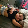 Selina is registered to the contest to win money with this photo: baby, bed, black_shirt, blanket, child, cozy, cute, diaper, face, hair, hand, indoors, infant, peaceful, pillow, relaxing, resting, sleeping, soft_lighting, toddler