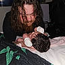 Selina joined the competition — help win amazing prizes! man, baby, newborn, mittens, beard, long_hair, blanket, bed, cat, black_cat, indoor, portrait, tender_moment, face, person, hair, animal, resting, soft_lighting, closeup