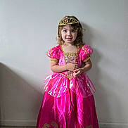 Ellie is registered to the contest to win money with this photo: child, girl, princess, dress, pink, tiara, smile, curly_hair, standing, indoor, floor, wall, costume, portrait, happy, young, fashion, cute, person, clothing