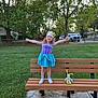 Ellie is registered to the contest to win money with this photo: child, girl, princess, crown, dress, bench, toy, stuffed_animal, outdoor, grass, tree, sidewalk, smiling, happy, curly_hair, park, summer, playful, sandals, sock