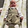 baby, smiling, infant, changing_mat, lion_pattern, dress, white_tights, carpet, happy, child, cute, indoors, person, apparel, fabric, lying_down, small_child, portrait, clothing, soft_lighting