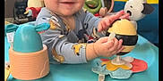 Braxton Jaxx is registered to the contest to win money with this photo: activity_table, baby, child, clothing, colorful, cute, face, fun, furniture, happy, indoor, infant, minion, person, plastic, play, smile, table, toy, young_child
