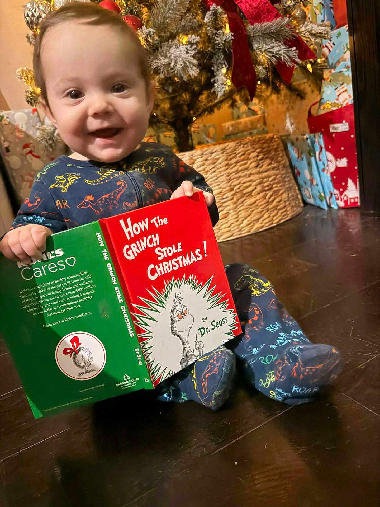Braxton Jaxx joined the competition — help win amazing prizes! baby, child, christmas_tree, holiday, book, reading, dinosaur_pajamas, floor, gift_wrap, decorations, smiling, indoor, festive, toddler, present, cute, happy, christmas, cozy, seasonal