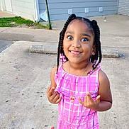 Armani is registered to the contest to win money with this photo: child, girl, braided_hair, pink_dress, necklace, playful, outdoor, sidewalk, concrete, happy, cute, beads, person, smiling, tongue_out, eyes_wide, summer, casual, young, funny_face