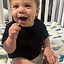 Braxton is registered to the contest to win money with this photo: toddler, child, smiling, happy, dimples, black_shirt, shorts, crib, bed, dinosaur_print, baby, indoor, person, cute, laughing, young_child, skin, hand, foot, playful