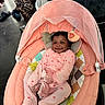baby, infant, smile, pink_onesie, baby_seat, mesh_canopy, soft_toys, leopard_print_pants, colorful_shoes, dark_floor, happy, cute, child, portrait, indoor, cushion, person, footwear, patterned_clothing, baby_accessory