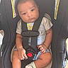 baby, buckled, car_seat, child, face, gray_clothing, hands, indoors, infant, infant_carrier, legs, photography, portrait, safe_travel, safety_harness, serious, shorts, sitting, socks, vehicle