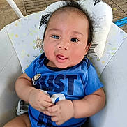 Kingston is registered to the contest to win money with this photo: baby, child, infant, portrait, smiling, happy, sitting, blue_shirt, clothing, face, eyes, hair, hands, arms, cushioned_seat, pillow, outdoor, patio, daylight, close_up