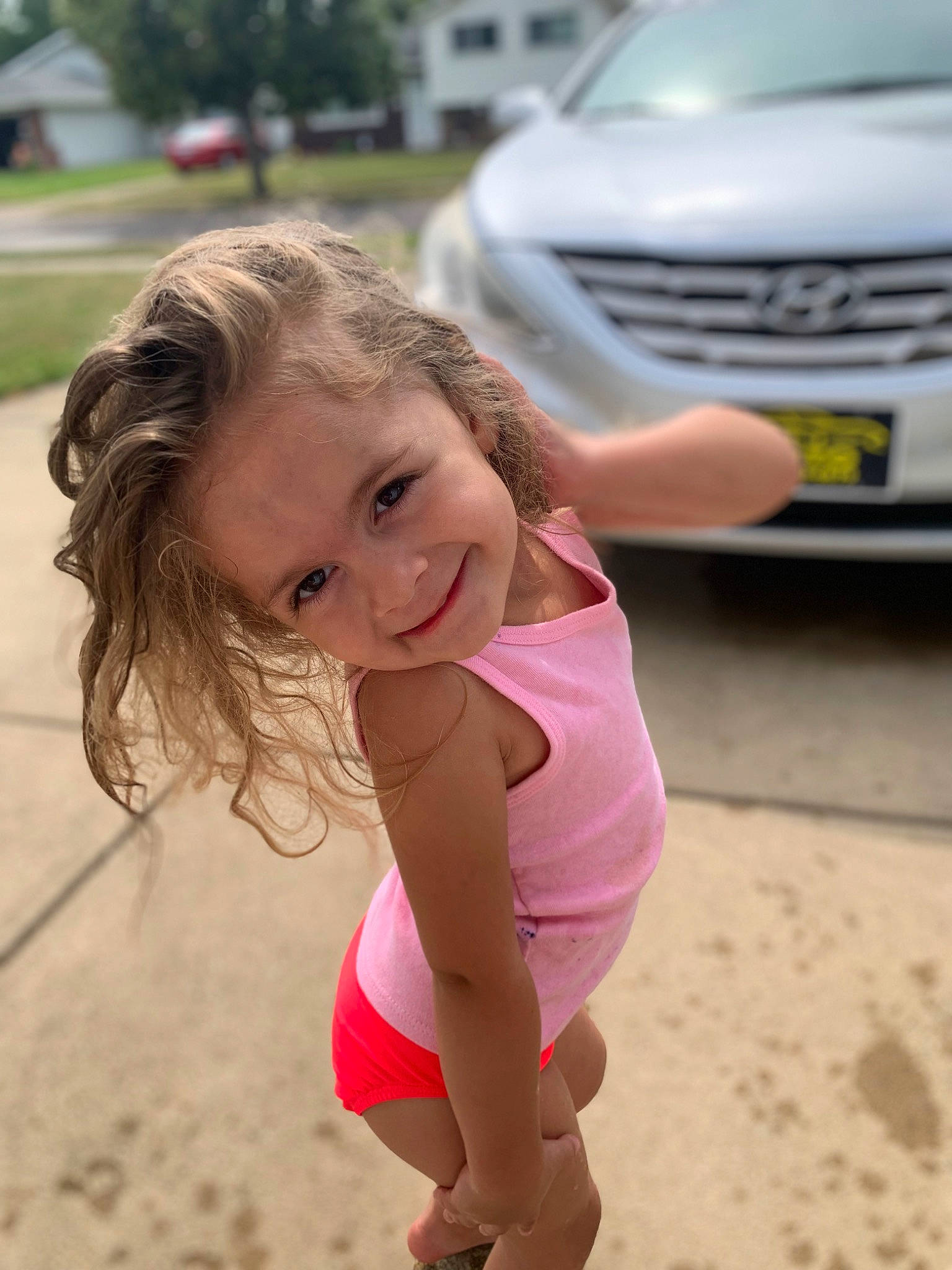 Aria is registered to the contest to win money with this photo: automotive_design, automotive_exterior, automotive_lighting, automotive_tire, bumper, car, face, grass, grille, happy, head, headlamp, hood, joy, leg, leisure, motor_vehicle, person, thigh, toddler