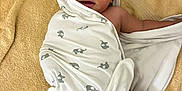 Aqeil is registered to the contest to win money with this photo: baby, towel, wrapped, elephant_print, lying_down, soft_texture, curious_look, indoors, child, infant, skin, face, head, blanket, floor, comfort, cute, expression, person, legs