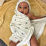 baby, towel, wrapped, elephant_print, lying_down, soft_texture, curious_look, indoors, child, infant, skin, face, head, blanket, floor, comfort, cute, expression, person, legs