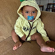 Aqeil joined the competition — help win amazing prizes! toddler, child, pacifier, hoodie, yellow_clothing, sitting, couch, indoor, home, furniture, baby, face, eyes, expression, casual, person, living_room, cute, comfort, relaxation