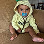 toddler, child, pacifier, hoodie, yellow_clothing, sitting, couch, indoor, home, furniture, baby, face, eyes, expression, casual, person, living_room, cute, comfort, relaxation